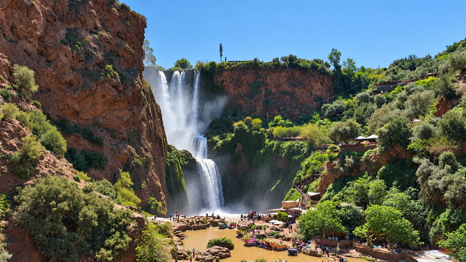 Ouzoud Waterfalls cascading between red cliffs and green trees in Morocco